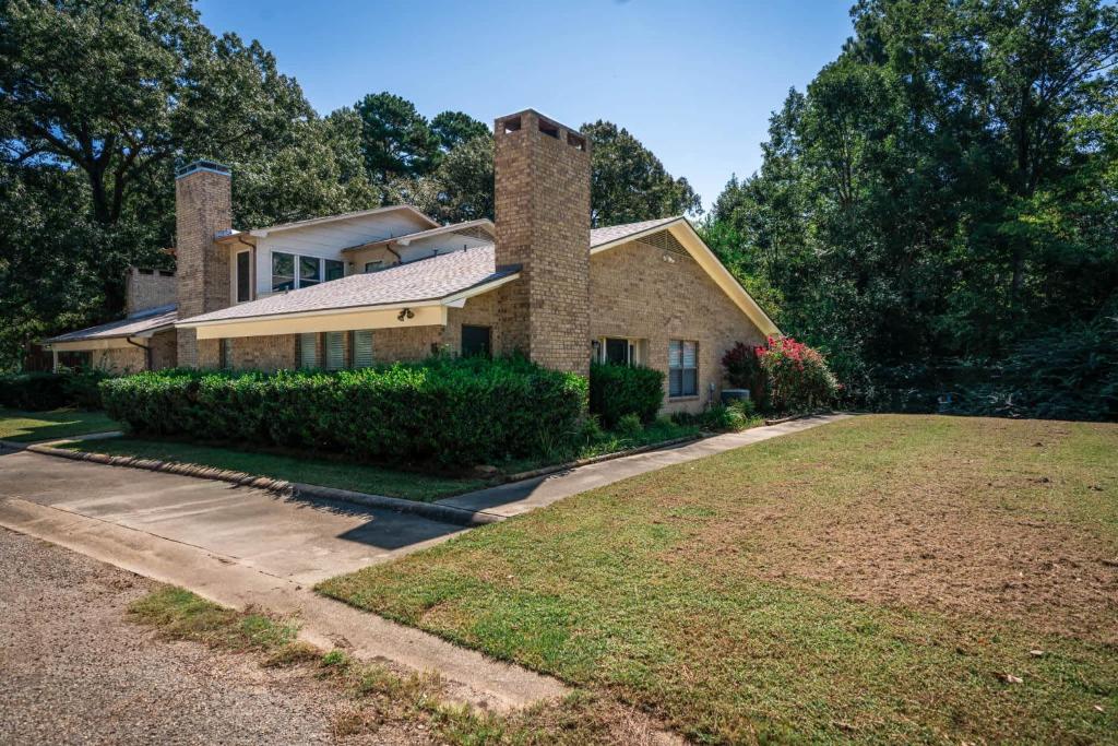a house with two chimneys on top of a yard at Woodland Springs in Gladewater
