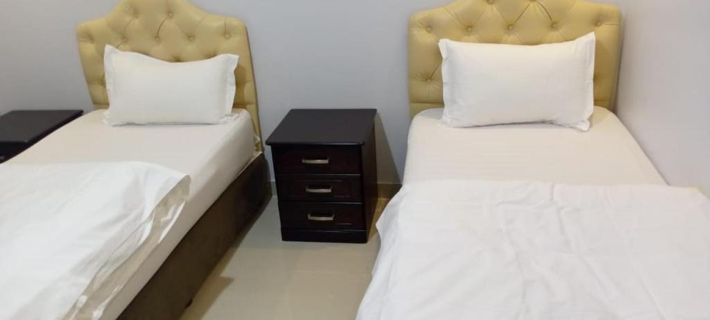 a bedroom with two beds and a nightstand between them at رفا للشقق المخدومة in Quai