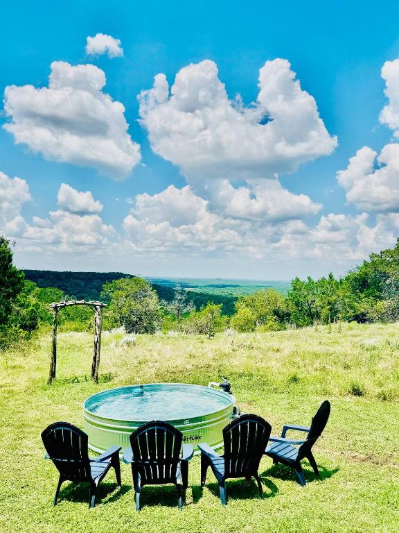 a group of chairs and a table in a field at Cliffside Cabin @ High Hope Ranch Cowboy POOL! in Glen Rose