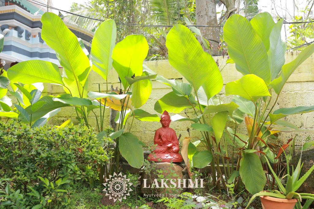 una statua di Buddha seduta in mezzo alle piante di Lakshmi Ayurveda & Yoga Apartment a Kovalam