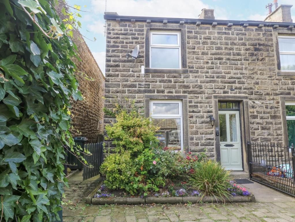 a brick house with a white door and some plants at Centenary Cottage in Skipton