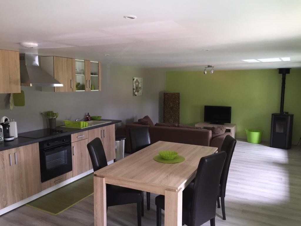 cocina y sala de estar con mesa de madera y sillas en A la Ferme Bleue, en Nayemont-les-Fosses