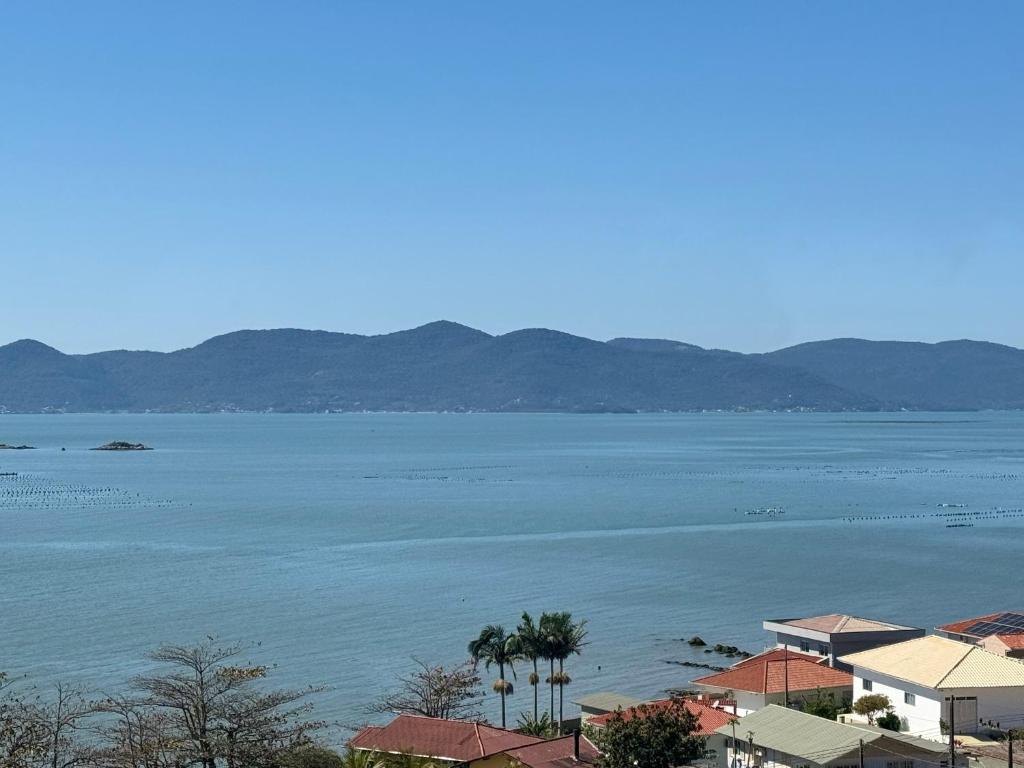 a large body of water with houses and palm trees at Oceanfront apartment with beautiful view in Palhoça
