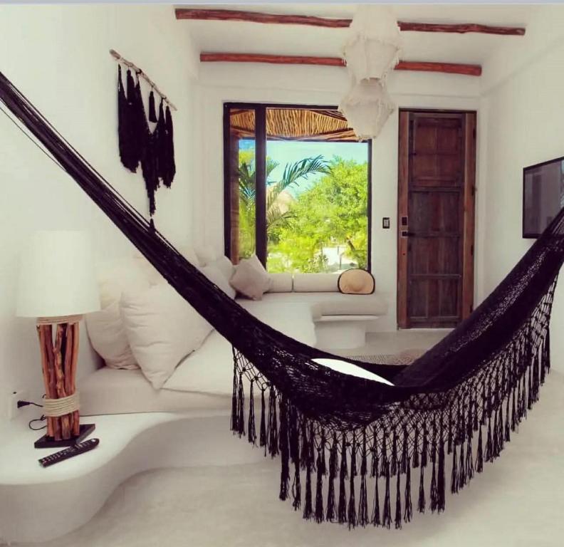 a hammock in a room with a couch and a window at Ikal Island Garden in Isla Mujeres