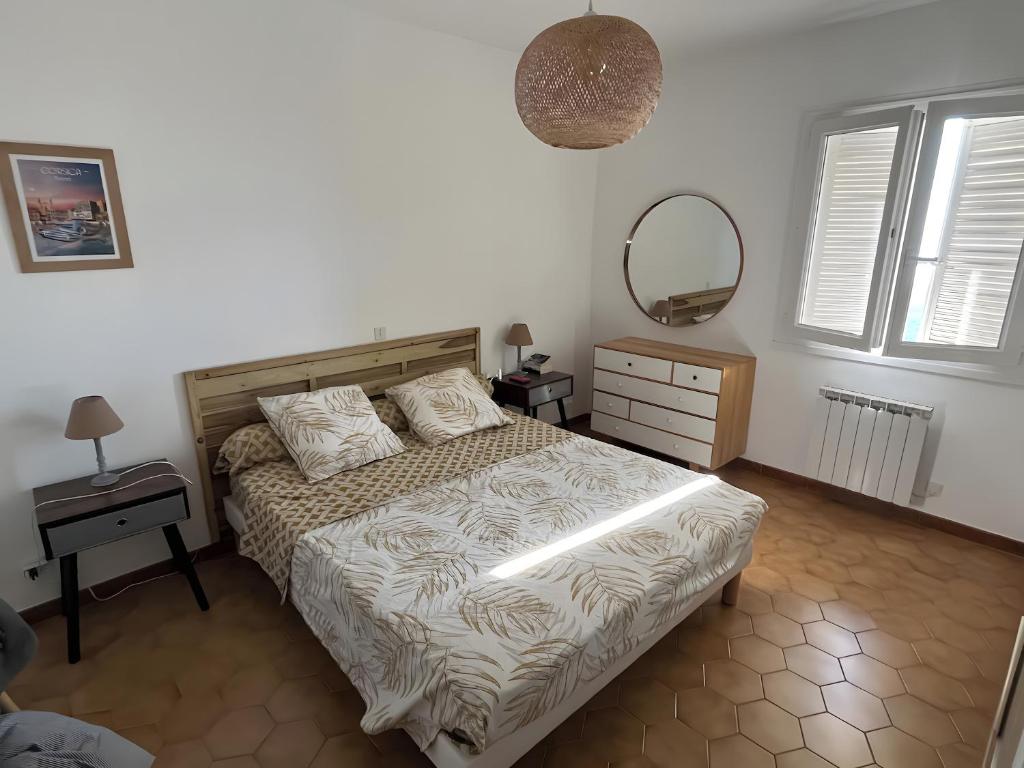 a bedroom with a bed and a mirror on the wall at Maison tout confort in Cervione
