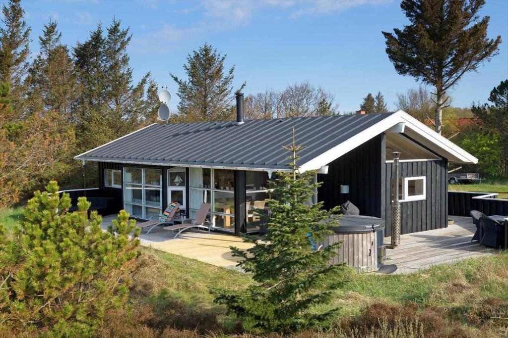 a small black cottage with a porch and a patio at TV1597-Albaek-Albaekvej-78 in Ålbæk