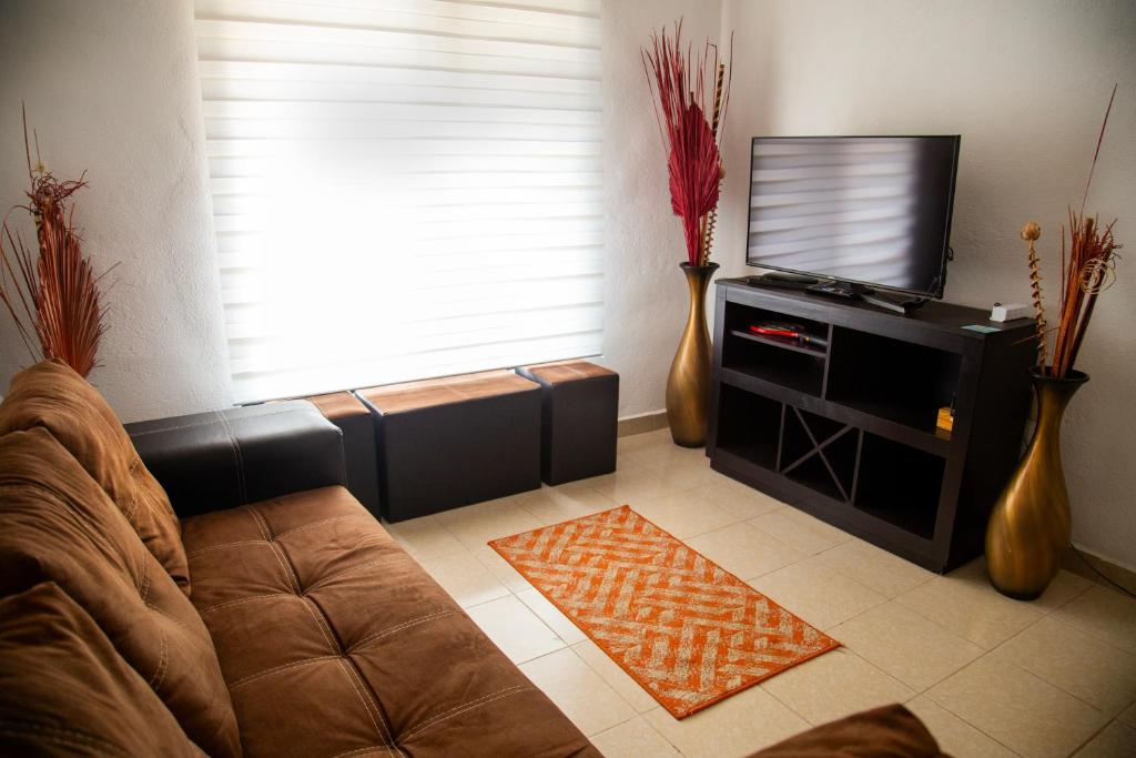 a living room with a couch and a flat screen tv at La casa de Yaya in Puerto Escondido