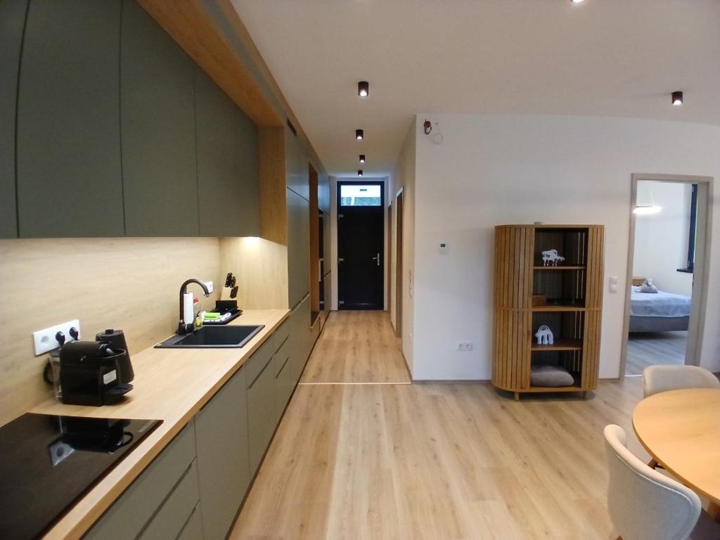 a kitchen with green cabinets and a wooden floor at Fenyvesliget Apartmanok IV in Balatonfenyves
