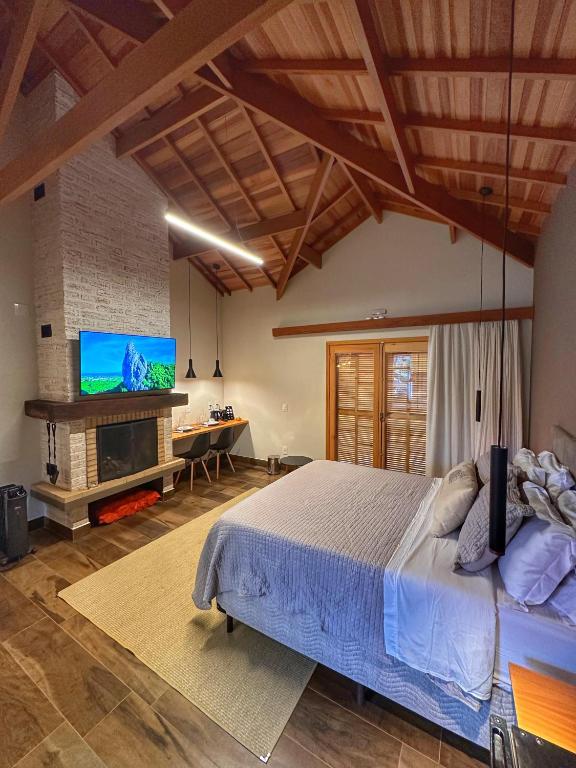 a bedroom with a large bed and a tv at Terrace Chalés in Monte Verde