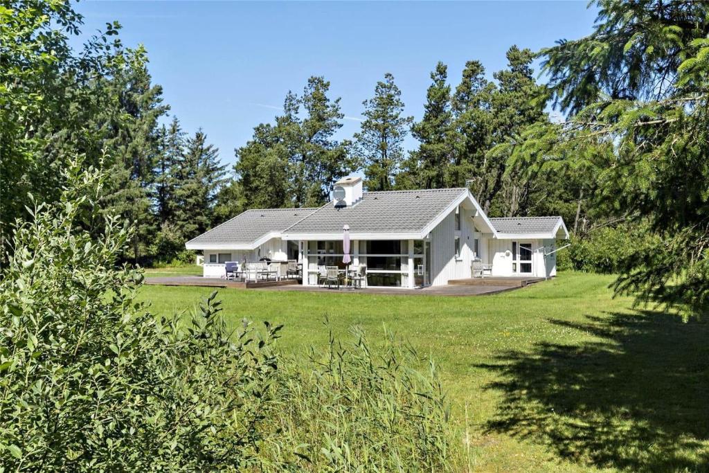 a white house on a lawn with trees at TV1285-Bindslev-Tannisgardvej-16 in Bindslev