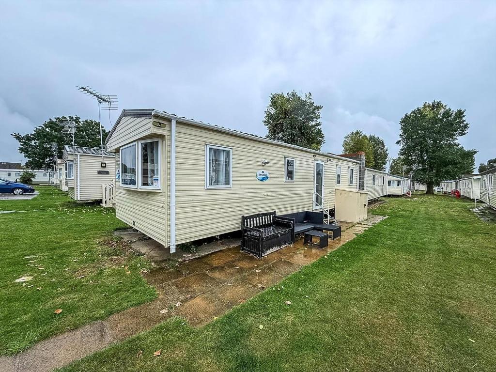 a mobile home with a bench in a yard at Superb 8 Berth Caravan At Highfield Grange Ref 26706Wr in Clacton-on-Sea