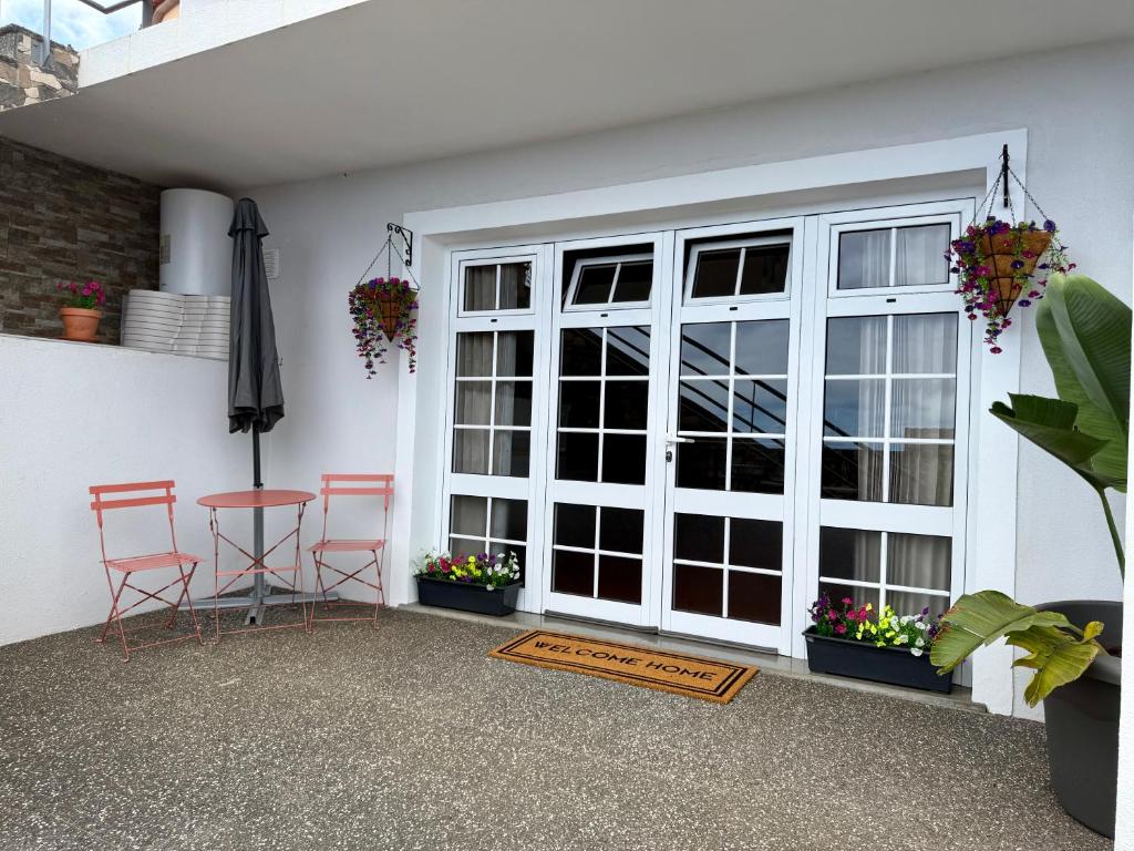 a patio with a door and two chairs and an umbrella at Airport Oasis in Santa Cruz