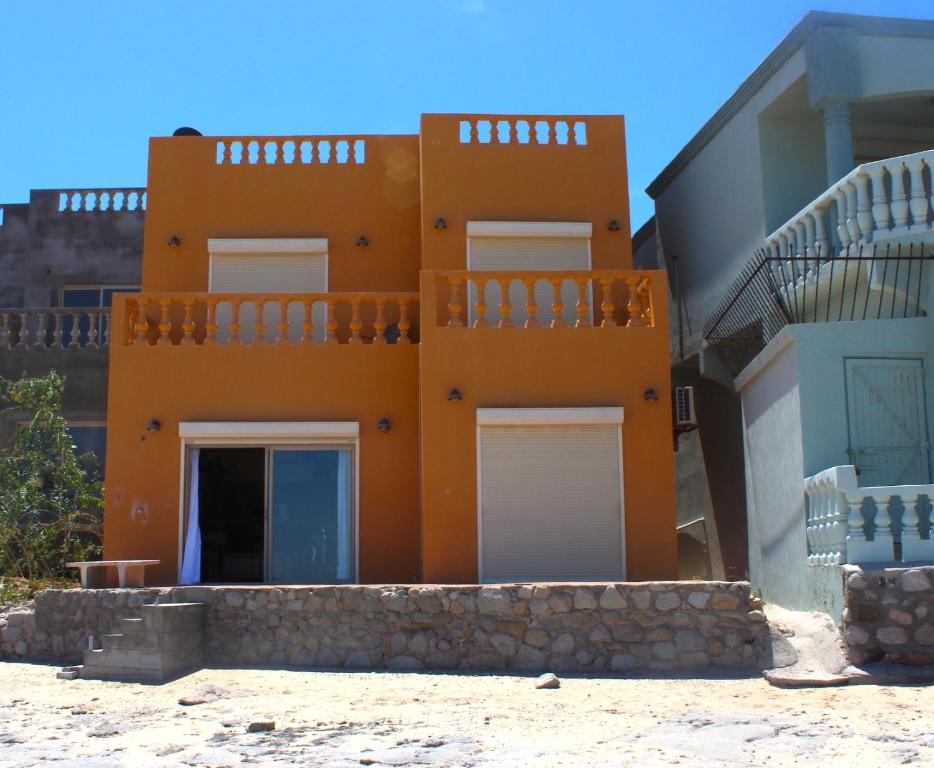 an orange building with white doors and a balcony at Casa Arco Iris in La Choya
