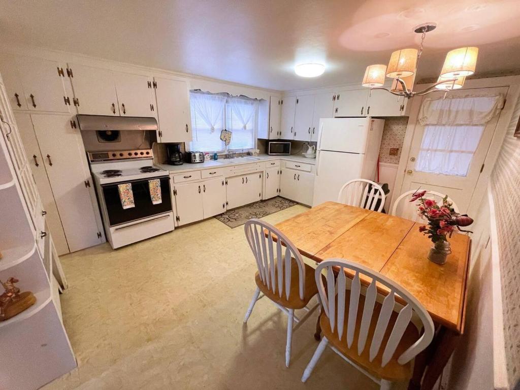 a kitchen with white cabinets and a wooden table and chairs at Little Miss Cottages - 173 House in Old Orchard Beach
