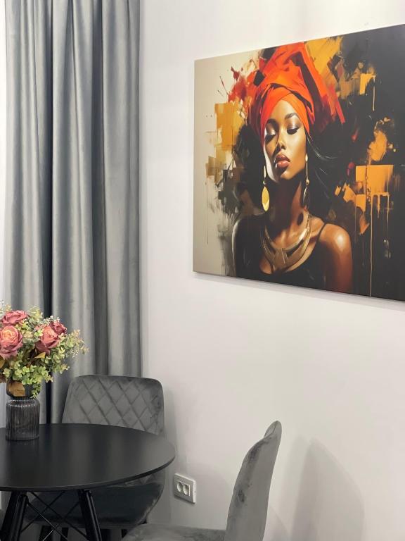 a painting of a woman on a wall with a table at Harmony Apartments Airport in Iaşi
