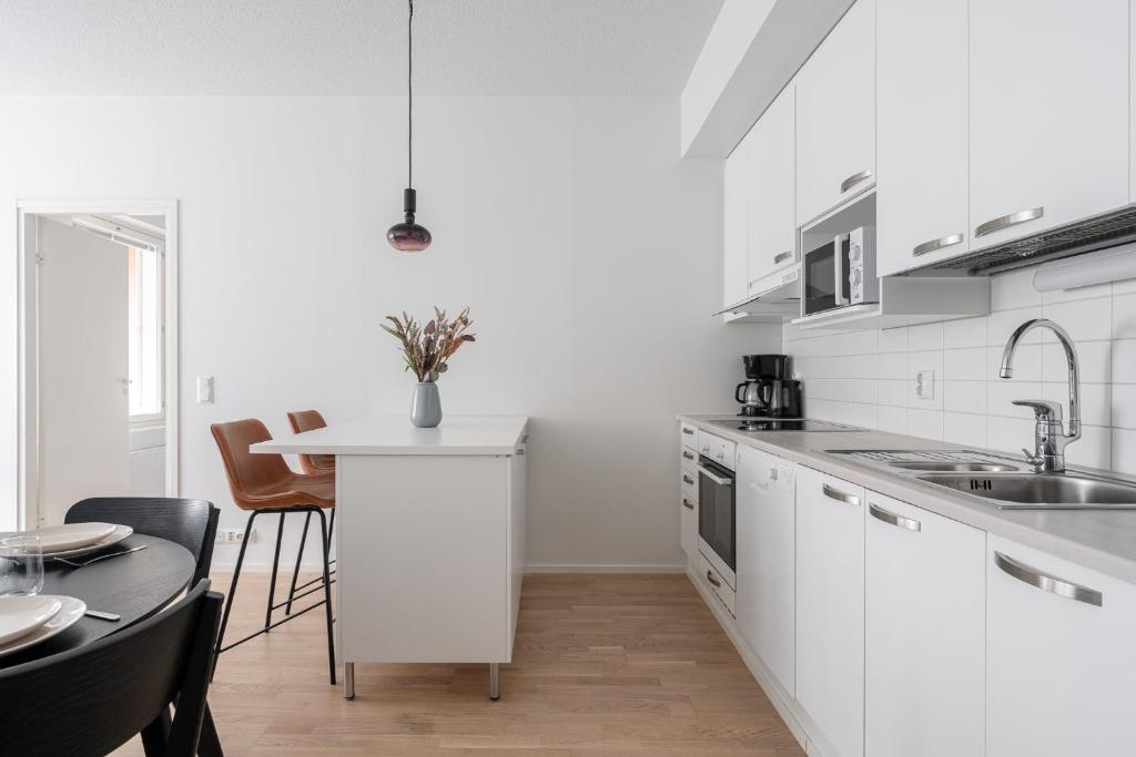a kitchen with white cabinets and a table with chairs at "Ketlari"- Homelike 1BR Apartment with Sauna in Historic Area, Hosted by 2ndhomes in Tampere
