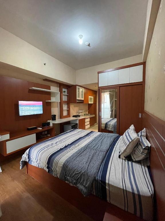 a bedroom with a large bed and a television at The Avenue Parkland Serpong by Ngeroomin in Babakan