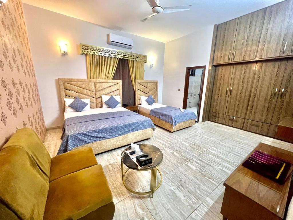 a hotel room with two beds and a couch at Amada Family Guest House in Karachi