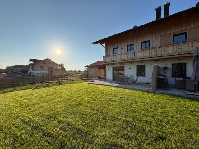 a large yard next to a building with a grass field at Entspannung auf dem Land in Dietramszell