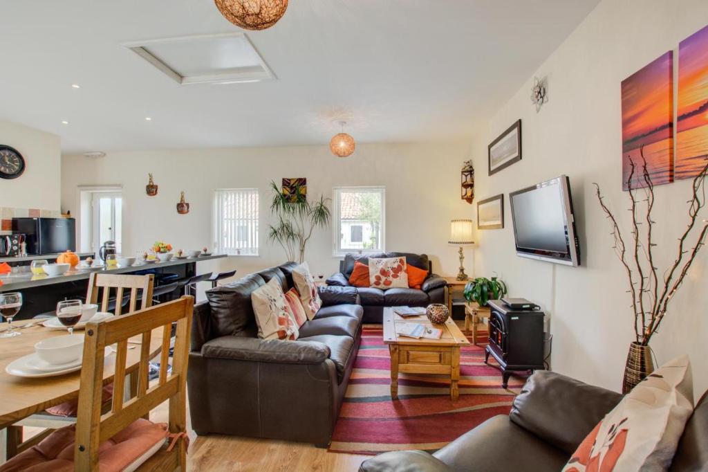 een woonkamer met een bank en een tafel bij Farriers Cottage in Blofield