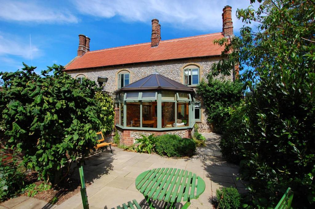 a brick house with a conservatory in front of it at Folly Cottage in Bodham