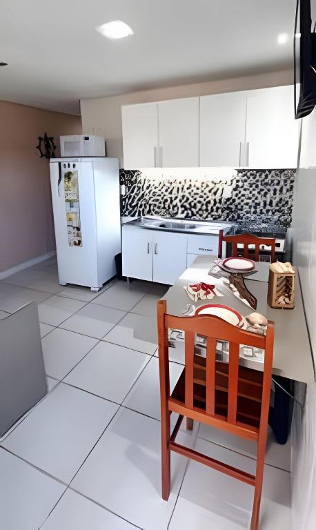 a kitchen with a table and chairs and a refrigerator at Apartamento térreo climatizado próximo a praia in Itapema