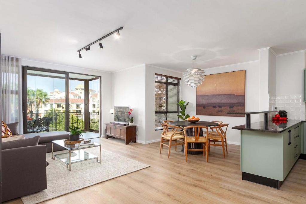 プリングル・ベイにあるLuxurious Palm View Apartment Cape Townのテーブルと椅子のあるキッチンとリビングルーム