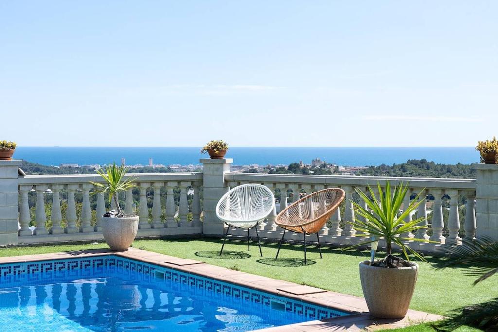 Un patio con dos sillas y una piscina. en Private Pool Sea Views Bellvei Villa Barcelona, en Calafell