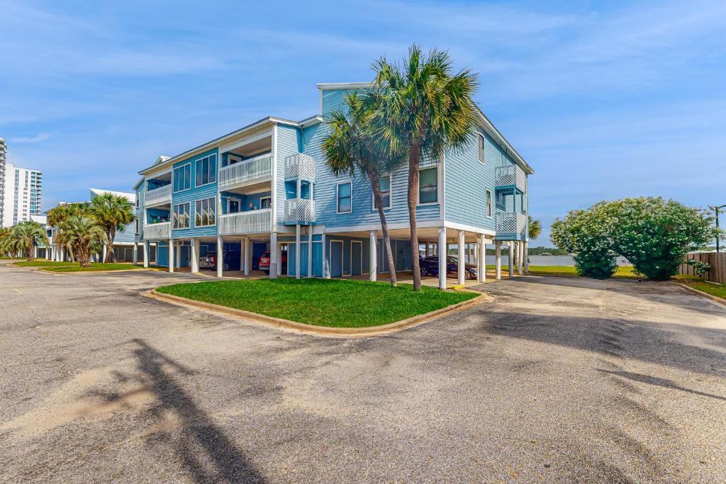 a blue building with palm trees in front of a street at Sea Oats A203 in Gulf Shores