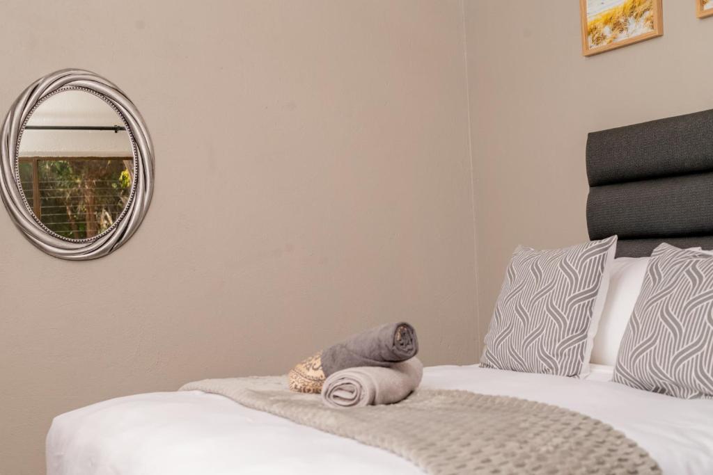 a bedroom with a white bed with a round mirror at SinoVilla397 in Pretoria