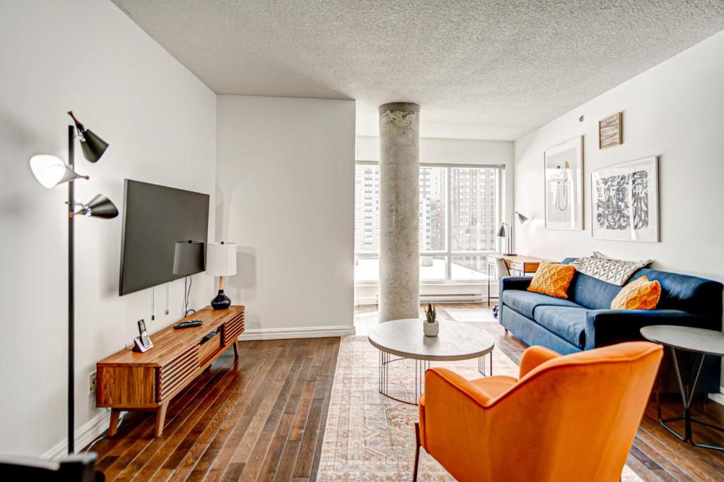 a living room with a blue couch and a tv at Le Mille Neuf Apartments Modern Comfort in Downtown Montreal in Montréal