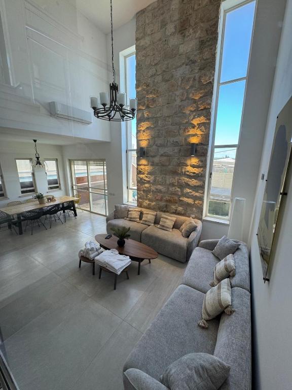 a living room with two couches and a stone wall at אלמה בוטיק - וילה מהממת עם בריכה פרטית מחוממת ומקורה in Shelomi