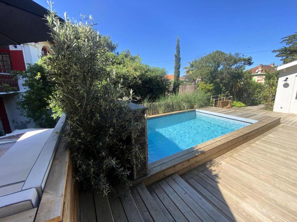 a swimming pool with trees and a wooden deck at Résidence 157-soulac Sur Mer - 157 - Maison de Charme de Style Basque avec Piscine Privée MAE-7391 in Soulac-sur-Mer