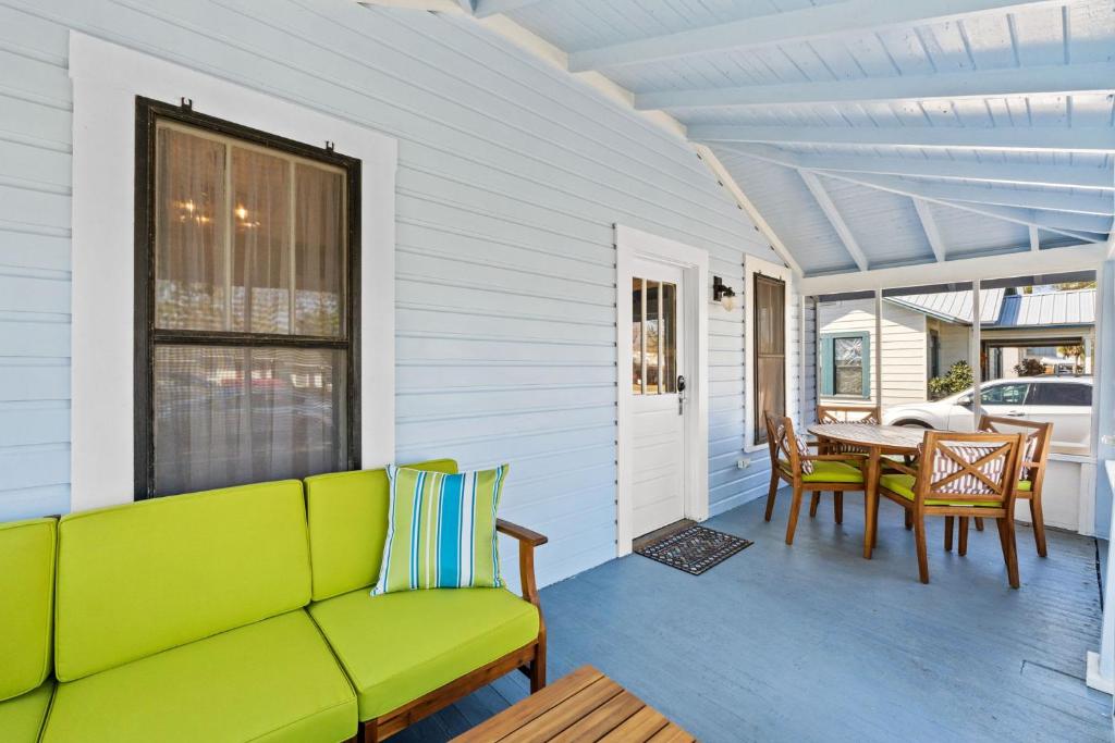 a green couch on a porch with a table and chairs at Mystic Moon- family friendly fenced yard pets welcome in Port Saint Joe