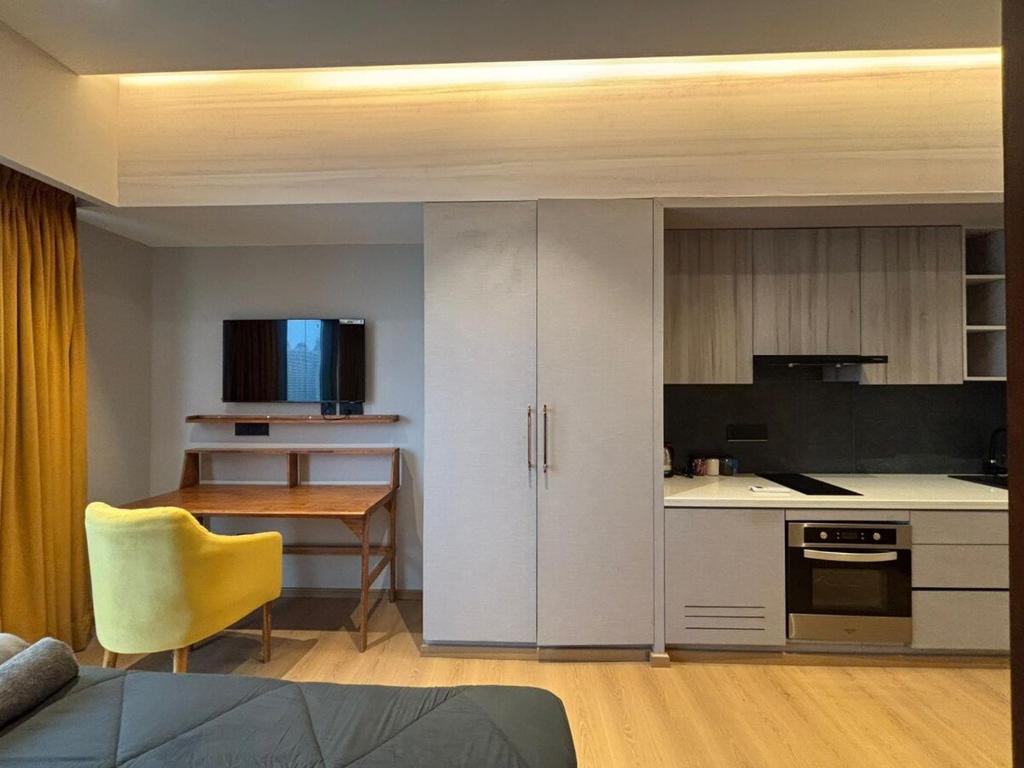 a kitchen with white cabinets and a table with a yellow chair at Sun n Sapphire - Book Half Day or Night in Ghaziabad