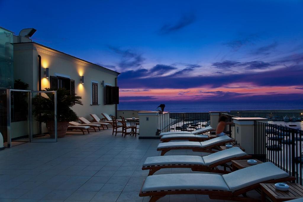 a row of chaise lounge chairs on a balcony at night at Hotel Villa Carolina in Ischia