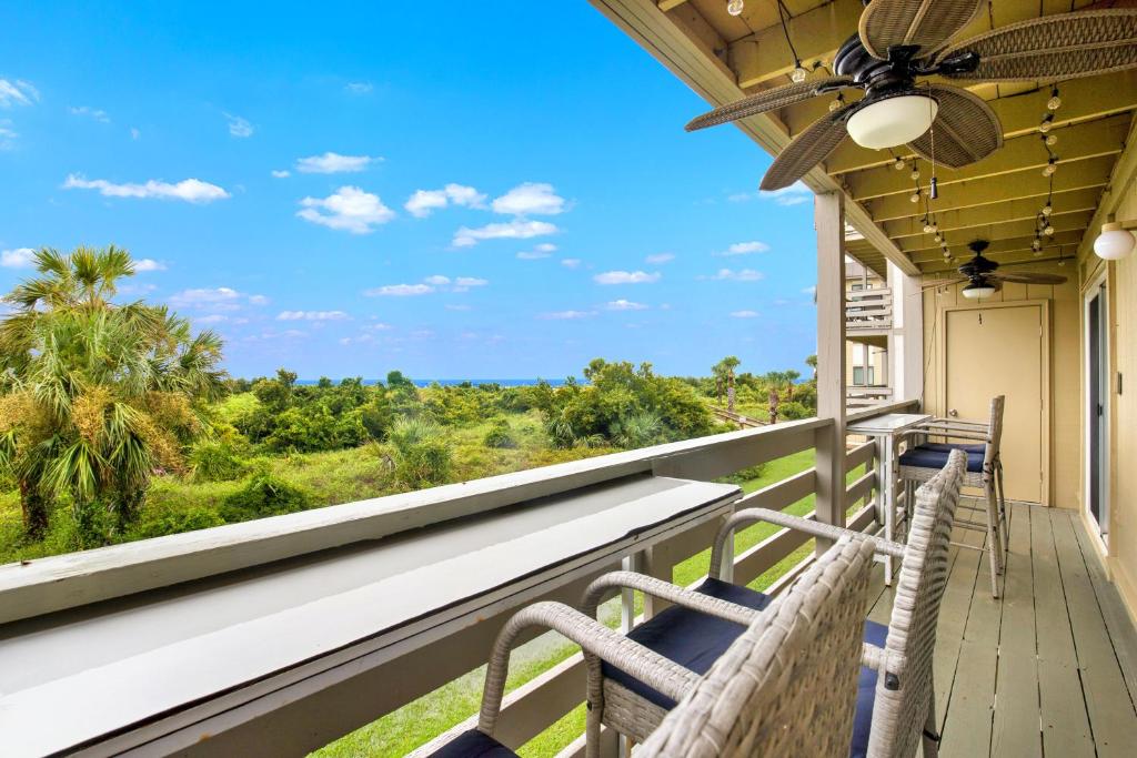 d'un balcon avec des chaises et une vue sur la jungle. dans l'établissement Happy Hour Tybee, à Tybee Island