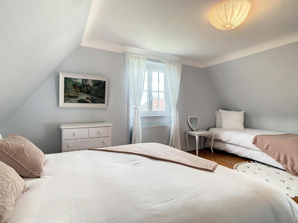 a bedroom with two beds and a window at Villa Camélias, appartements de Charme in Mittelwihr