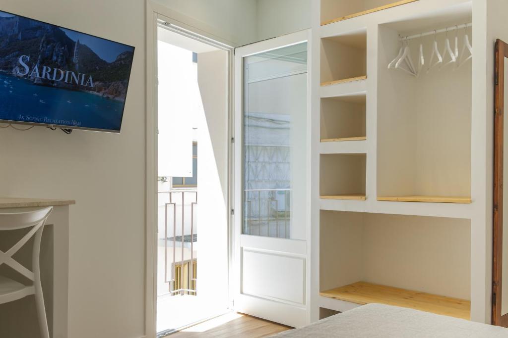 1 dormitorio con una puerta que da a un balcón en Emma's Downtown - Eco Design Rooms, en Olbia