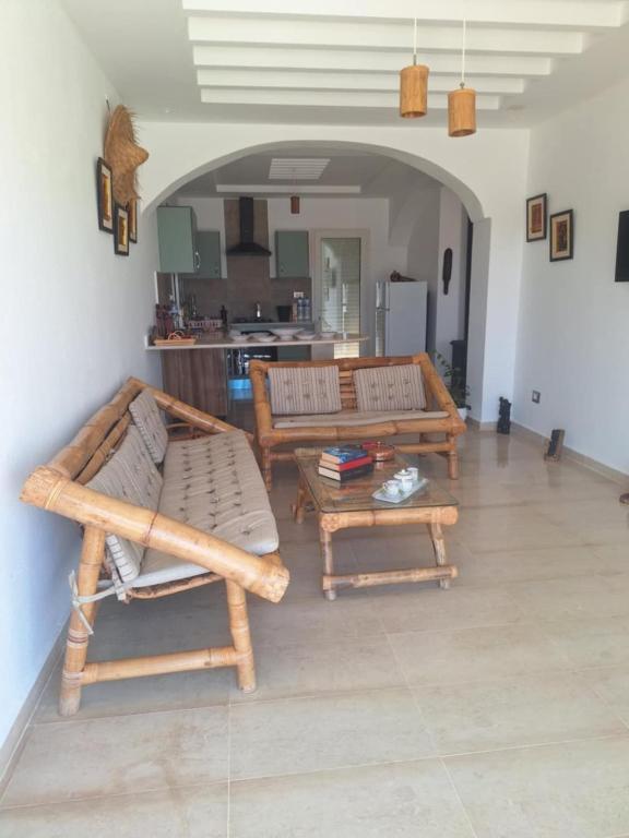 a living room with two benches and a table at Petite villa- Tamezrat- Kelibia in Kelibia