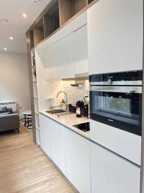 a kitchen with white cabinets and a microwave at Cozy Studio Apartment Near Heathrow Airport Terminal 4 - Unlimited Wi-Fi - Paid Parking in New Bedfont