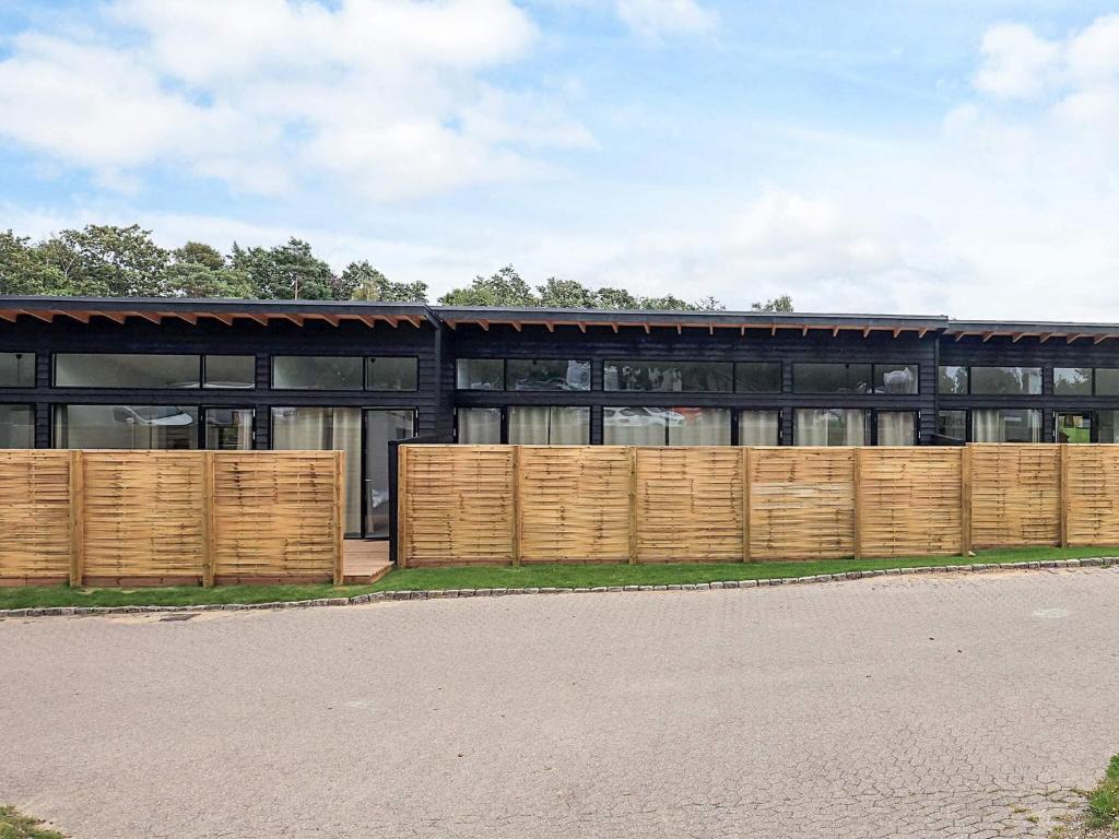 a black building with a wooden fence in front of it at 6 person holiday home in Gilleleje in Gilleleje