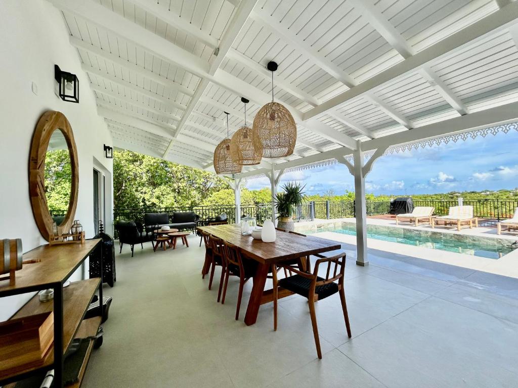 a dining room with a table and a pool at Villa Les Oliviers - Élégance & Sérénité in Les Terres Basses