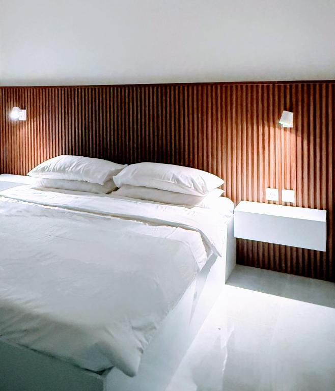 a bedroom with a large bed and a wooden wall at Onyx F62-2BHK modern classy furnished home with balcony in Muscat