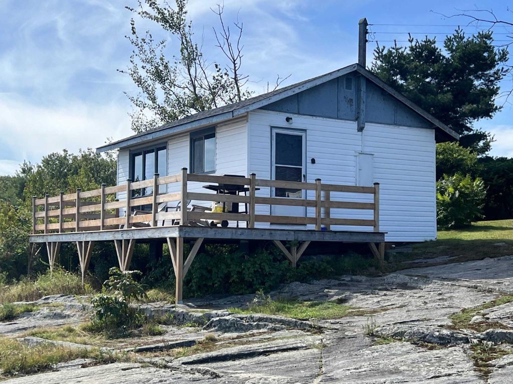 une petite maison blanche avec un porche en bois dans l'établissement Lakeview Cabin in Georgian Bay - Rockwood #11, à Dillon