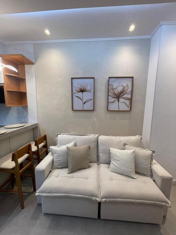 a living room with a white couch and a kitchen at Coração da Lapa no Centro RJ com Vaga in Rio de Janeiro