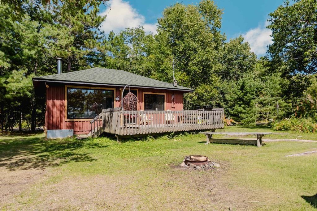 a cabin with a deck and a bench in the yard at 2-Bedroom Cottage #4 - Sand Bay in Dillon