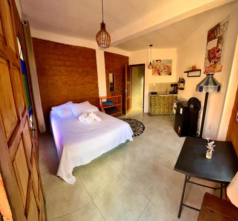 Un dormitorio con una cama blanca y una pared de ladrillo. en Vila Kuir Hospedagens, en Alto Paraíso de Goiás