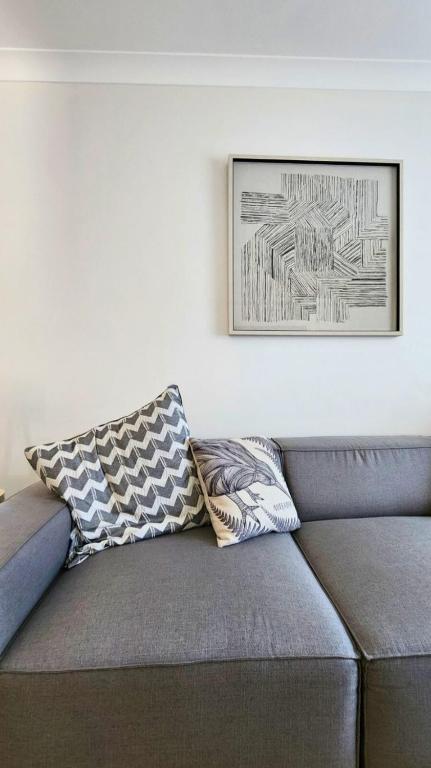un sofá con dos almohadas sentado bajo una foto en Charming Cottage Retreat Penrith, en Penrith