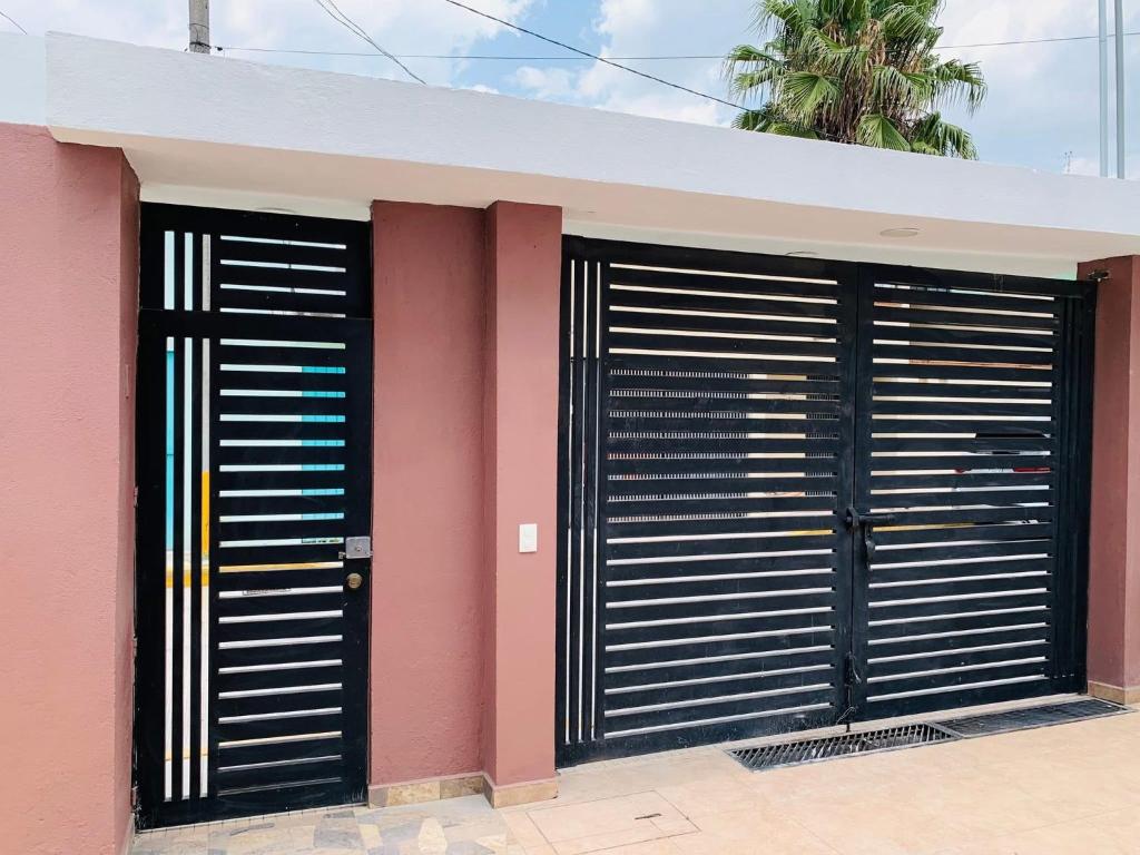 two black garage doors on a pink building at Casa de dos pisos,Ciudad Tolteca in Tula de Allende